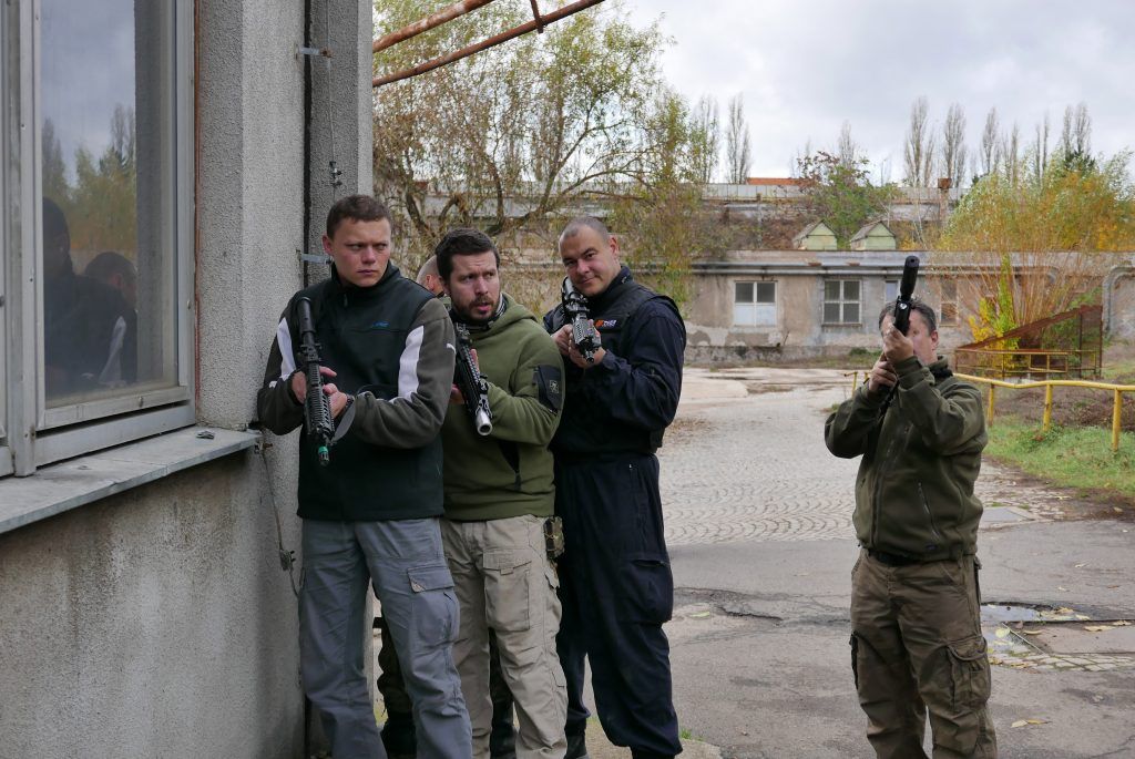 Tým postupuje podél budovy při taktickém nácviku CQB