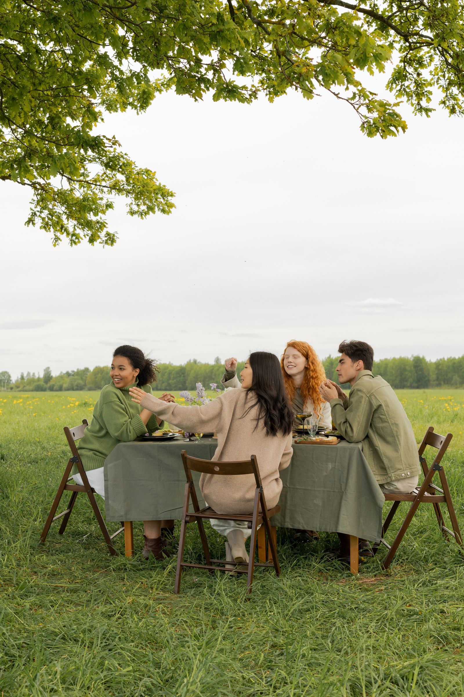 A group of participants eats lunch at a common table outside in nature during a break